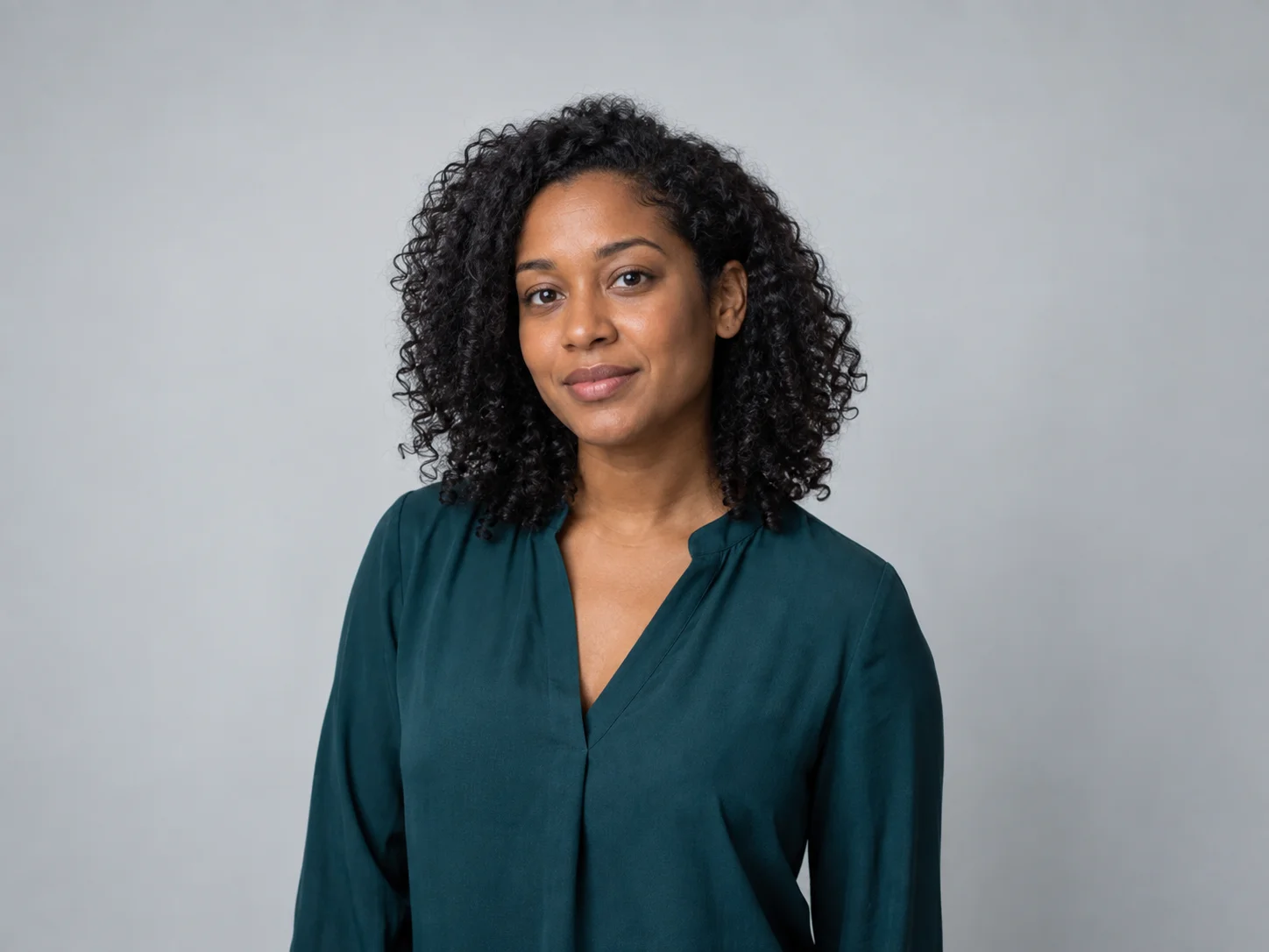 Fictional woman in a teal blouse against a plain gray backdrop before changing the background